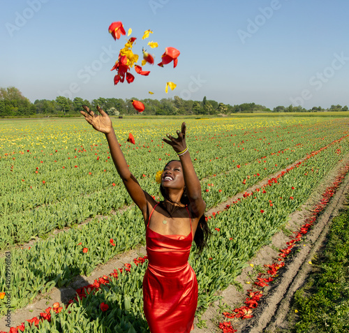 Joyful Young Woman Tossing Tulip Petals in Colorful Flower Field