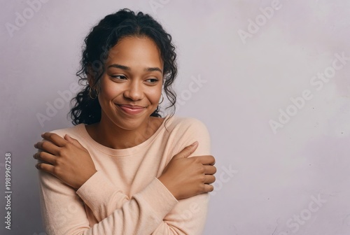 Smiling woman stands with crossed arms and expresses warmth against a plain background