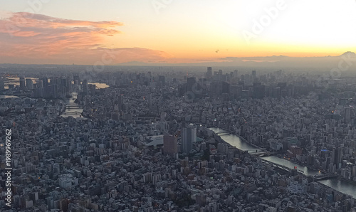 Aerial view of Tokyo at sunset from Tokyo Skytree, featuring dense urban skyline and rivers reflecting warm evening light