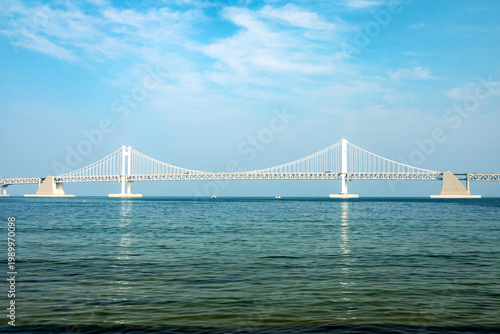 Canvastavla Gwangan Bridge suspension bridge spanning across calm blue sea water in Busan, S