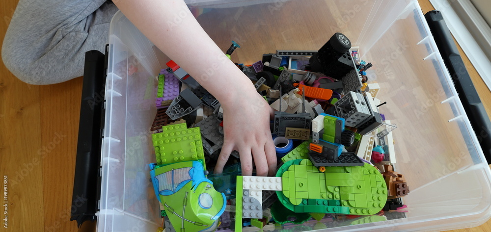 Fototapeta premium Kid playing with Lego. Assembly bricks or blocks in plastic. Hand visible.