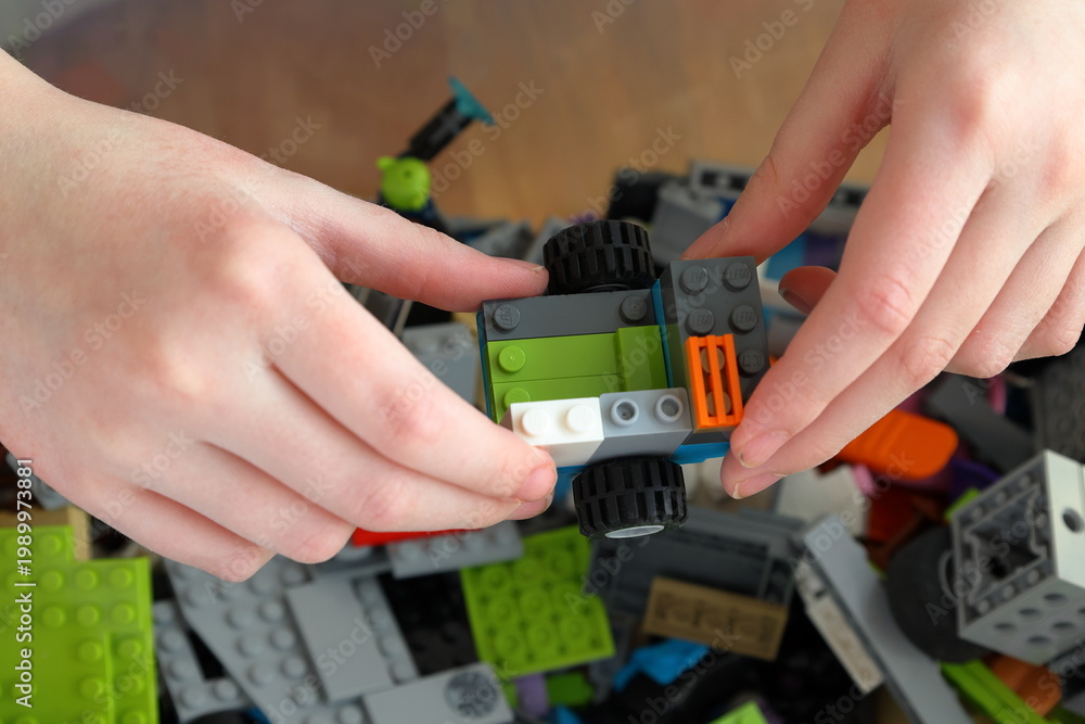 Obraz premium Kid playing with Lego. Assembly bricks or blocks in plastic. Hand visible.