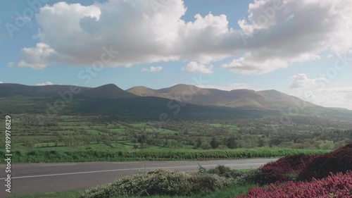 Serene landscape unfolding, inviting peaceful travel journeys through rolling green hills and winding roads in Ireland's Galtee Mountains, promoting personal growth and calm atmosphere.