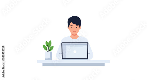A young man is sitting at a minimalist white desk while focused on working on his laptop next to a small green plant in a pot.