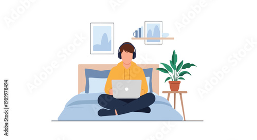 A young man wearing a yellow hoodie and headphones sits cross-legged on a bed while working or studying on a laptop in a cozy room.