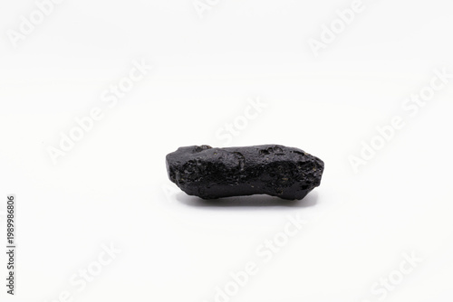 A close up image of a unpolished black Tibetan Tektite crystal on a white background. 