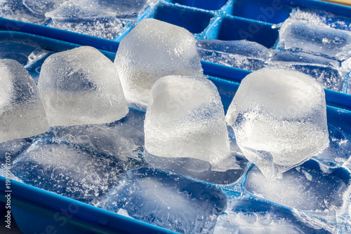 An image of several ice cubes turned upside down on a blue ice cube tray.  One of the ice cube trays is missing ice cubes.