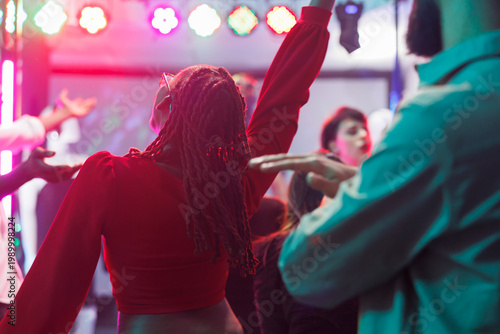 Canvastavla African american woman in red blouse jumping and dancing in crowded nighclub