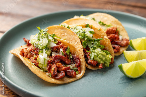 Foto Close up shot of three grilled pork tacos with corn tortillas, onions, guacamole