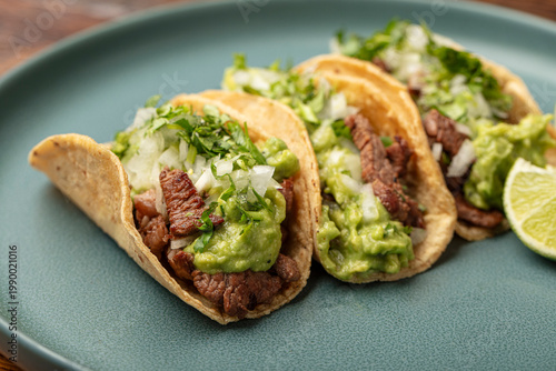 Fotografie Three Mexican carne asada steak street tacos on a plate with onions, cilantro, c
