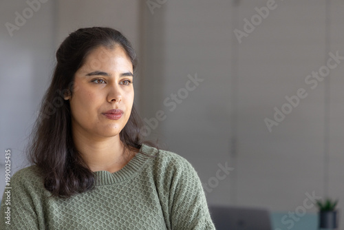 Photos Indian woman mid-twenties sitting facing right in soft light wearing green knit