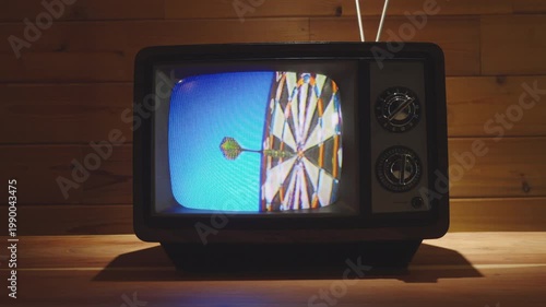Dart hitting dart board on Vintage Television in living room with wooden background. 