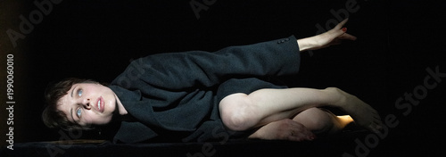 Foto This image features a figure in a dynamic posture, extending a hand outward, symbolizing searching or yearning for deeper meaning, enhanced by stark contrasts and dramatic lighting