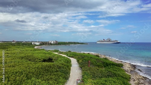 Aerial drone view of Mahahual coastline in Costa Maya, Mexico with cruise ship offshore, turquoise Caribbean waters, tropical vegetation and scenic shoreline.