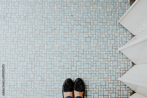 woman legs in blue jeans and in black shoes on mosaic tiles floor tile background