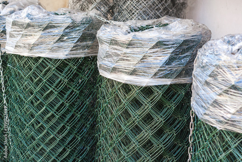 Stack of new chain-link wire mesh rolls at a construction site