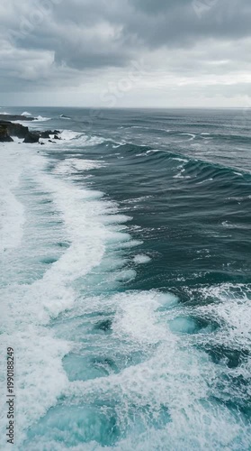 Turbulent Ocean Waves Crashing Against Rocky Shoreline Under Dramatic Overcast Sky