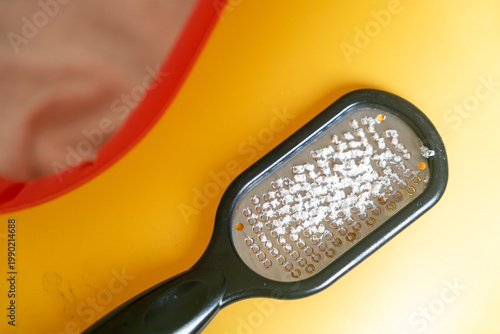 Fotografía Close-up of a black foot file covered with white dead skin flakes after callus removal, resting on a bright yellow background