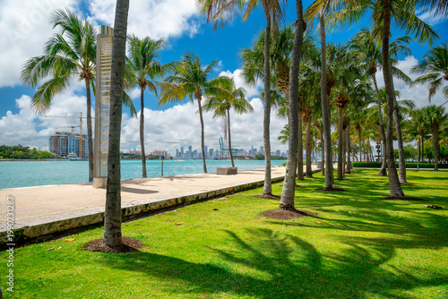 South Pointe Park walkway with palm trees and city skyline. Paved pedestrian path along the water with palm trees and Downtown Miami skyline in the distance.