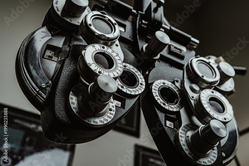 Detailed mechanical phoropter for professional optometry services. Side view of complex phoropter machine in dark professional setting for measuring eye refraction.