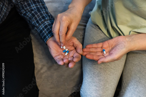 Hands sharing colored pills during a therapeutic session in a cozy home environment