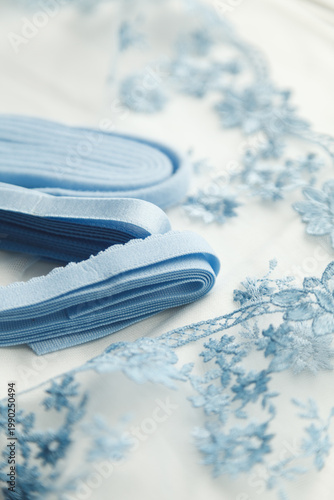 A close-up photo of tailor's tools: blue lace, elastic, spool. Photo grain added.