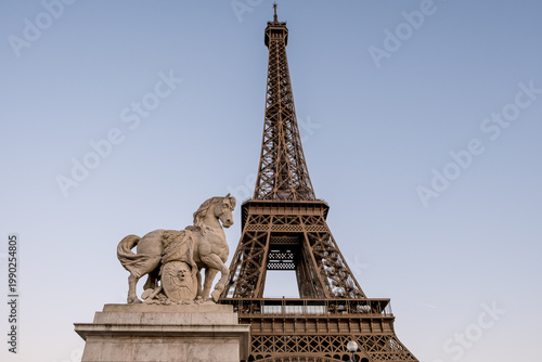 Paris, France – The Eiffel Tower framed by one of the monumental horse sculptures on Pont d'Iéna bridge. These statues represent warriors of the Napoleonic era.