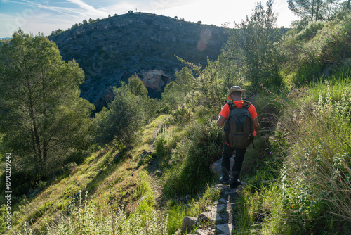 Hiker walking on a grassy path outdoors.