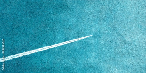 Jet leaves a long vapor trail high in the sky, creating a simple and atmospheric line against the blue background