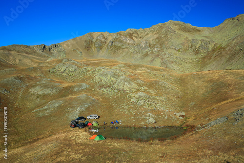 Image of people camping by a lake nestled among high mountains.
