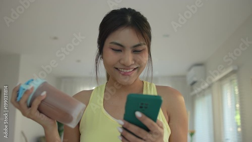 Young asian active woman drink whey creatine shake bottle eating diet food using phone calorie plan app after home sport workout. health care asia people happy relax protect aging life weight loss.