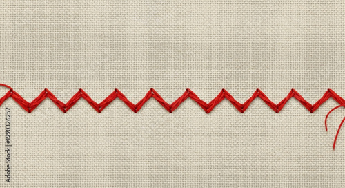 Red zigzag stitch on textured fabric close up.