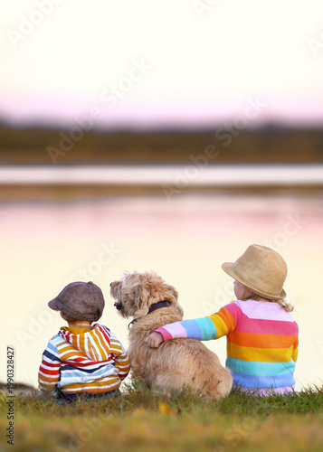 cute children with their dog sitting on a meadow near the sea