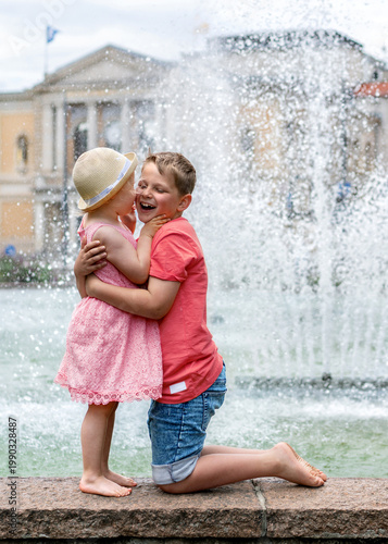 two laughing children hug each other at the fountain