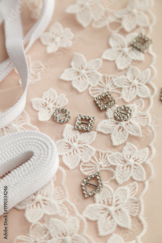 A close-up photo of tailor's tools: white flower lace,  decorations. Photo grain added.