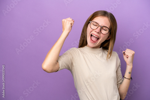 Young English woman isolated on purple background celebrating a victory