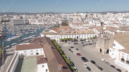 Aerial drone orbit around Largo da Sé square in Faro, Portugal with marina visible in the background.