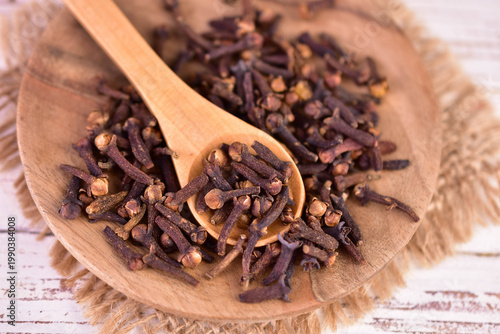 Clove spice in a wooden spoon on a plate. Aromatic seasoning.
