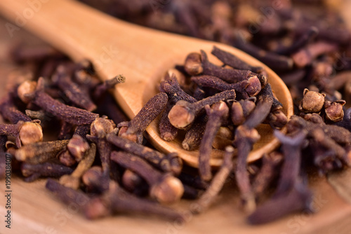 Spice cloves in a wooden spoon on a plate. Aromatic seasoning. Close-up.
