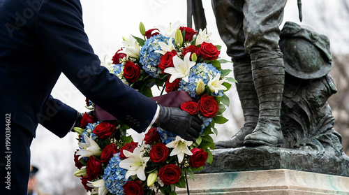 Hand laying decorative wreath at military monument for memorial day tribute ceremony