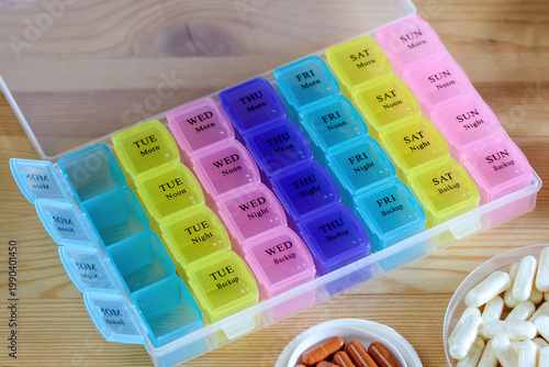 colorful weekly pill organizer with labeled days and capsules on table showing medication schedule healthcare routine and daily treatment management