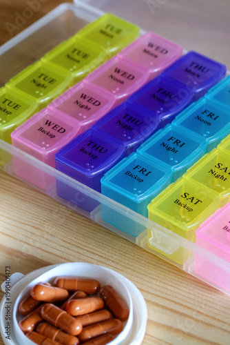 weekly pill organizer with capsules and tablets on wooden table medication schedule and healthcare routine