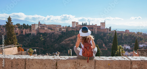 Φωτογραφία young woman with leather backpack overlooking alhambra palace in granada spain,