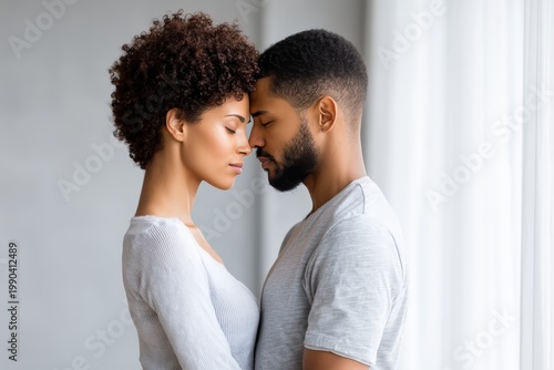 A tender moment between a couple standing close with foreheads touching, eyes closed, expressing intimacy and emotional connection.
