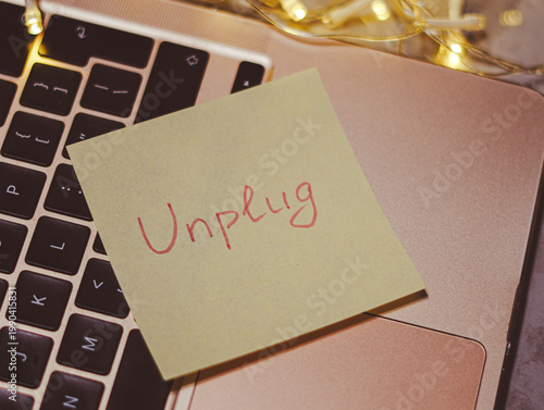 Φωτογραφία Sticky note with Unplug message on laptop keyboard with decorative lights