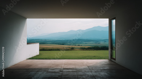 Modern architectural interior framing a vast landscape. A rectangular opening reveals a field, distant hills, and overcast sky