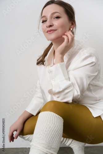 Woman sitting on the floor in white shirt and yellow leggings with white socks during indoor photo shoot