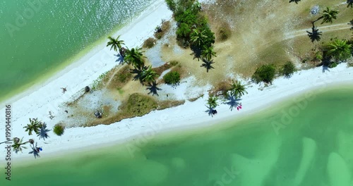 Aerial view of a pristine sandbar at Laem Haad Beach revealed at low tide. Crystal clear shallow water surrounds the white strip, drawing visitors to walk across one of most picturesque island scenes