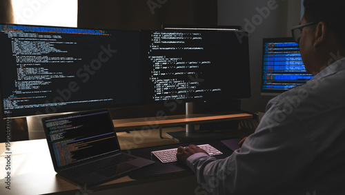 Bild auf Leinwand programmer working at a multi monitor computer setup with code on screens in a dark workspace, illustrating software development, coding, debugging, and technical workflow in office context