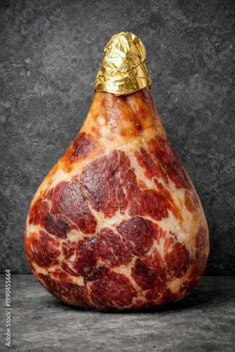 Culatello di zibello, a premium cured pork ham product, standing on a dark textured surface